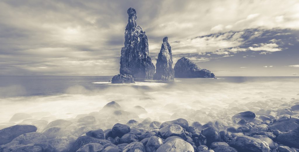 a rock formation over the sea with a cloudy sky